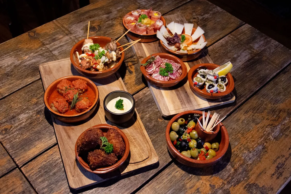 Small tapas dishes in earthenware bowls on a wooden table
