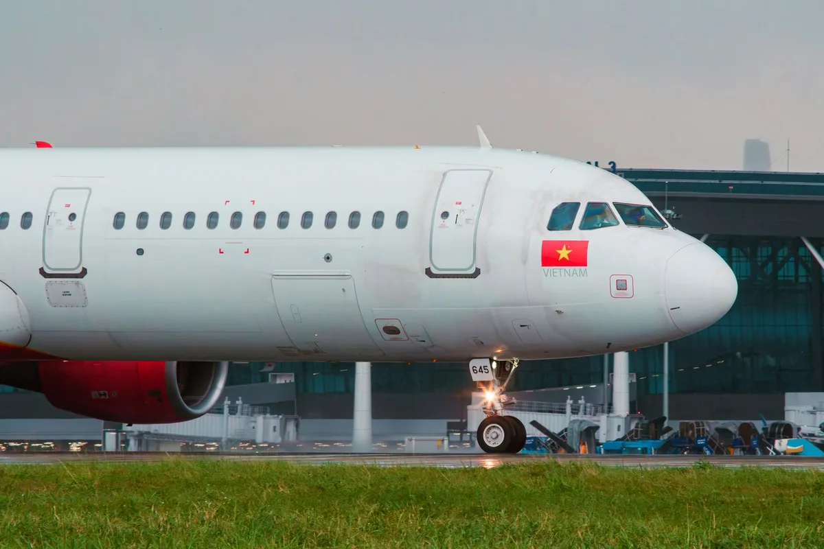 A passenger jet at the gate in Vietnam, red engine and the national flag on its fuselage