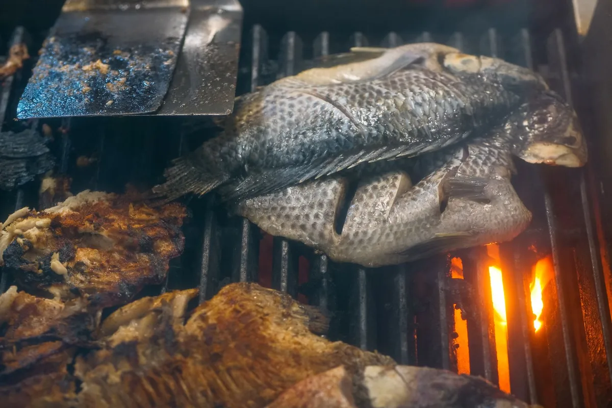 A whole fish grilling over charcoal, the Bai Chay seafood ritual