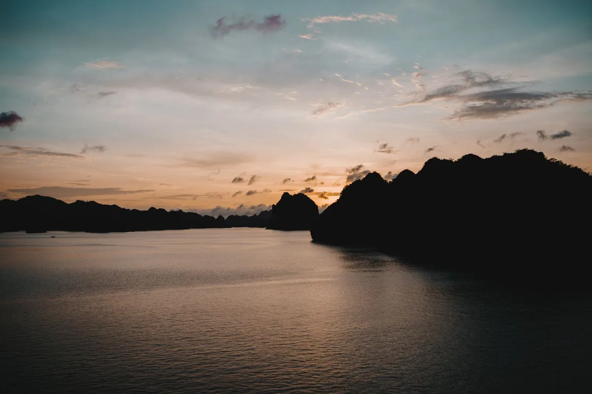 Karst silhouettes at dusk over still water in the bay