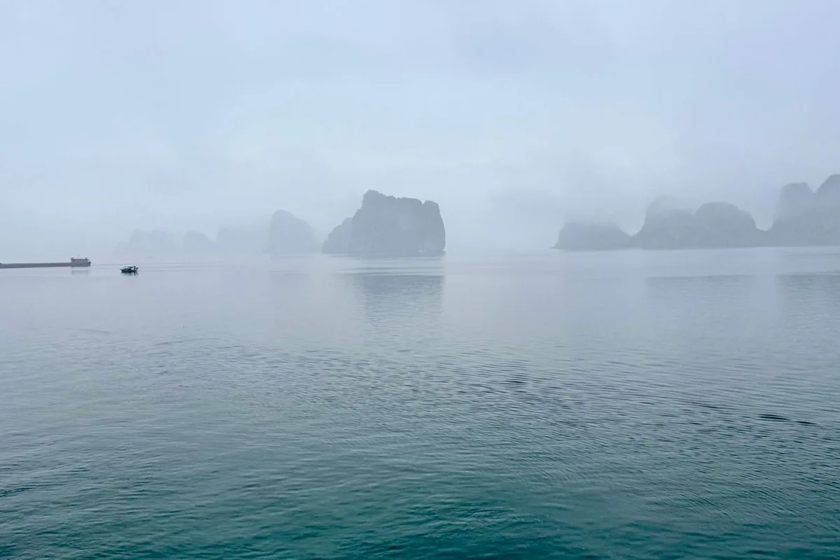 Winter mist hanging over the karsts and a lone boat on the bay