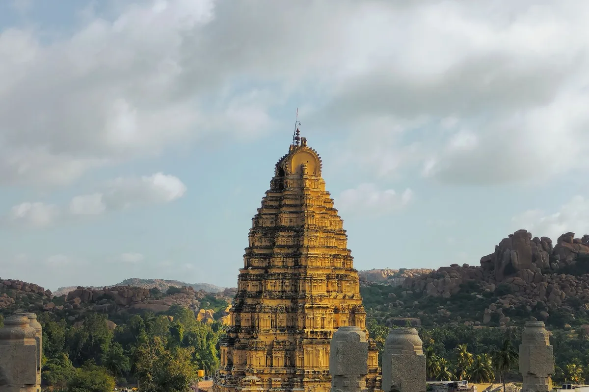 The Virupaksha Temple tower rising over the ruins and boulder hills of Hampi