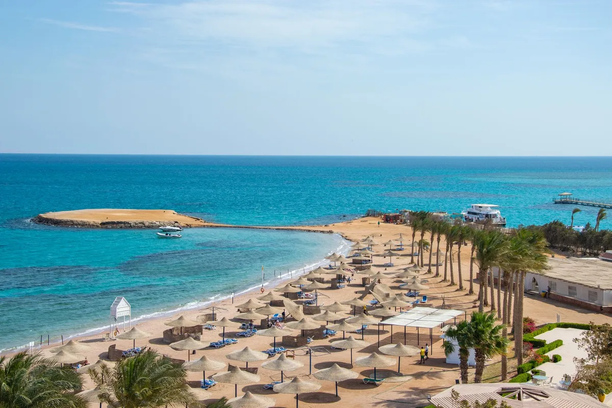 A resort beach with umbrellas and a small island offshore, Hurghada