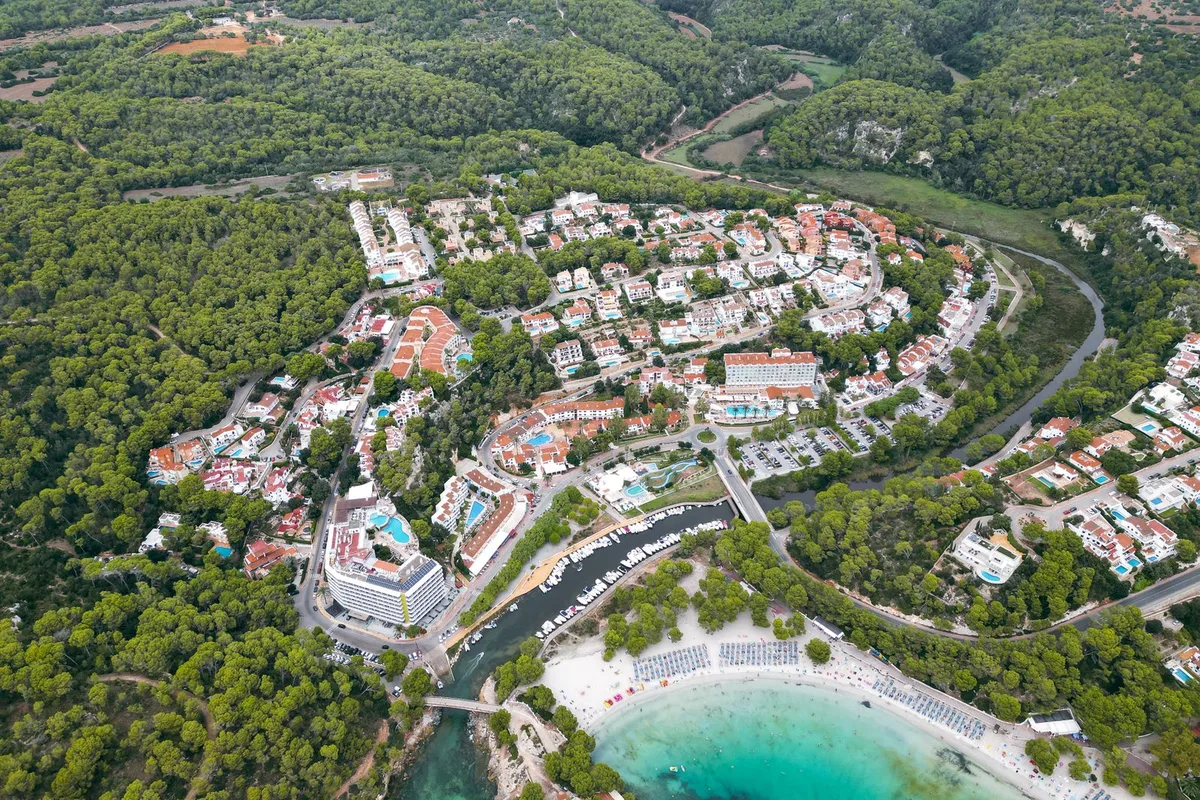 An aerial view of a cala and its village on Ibiza's green north coast