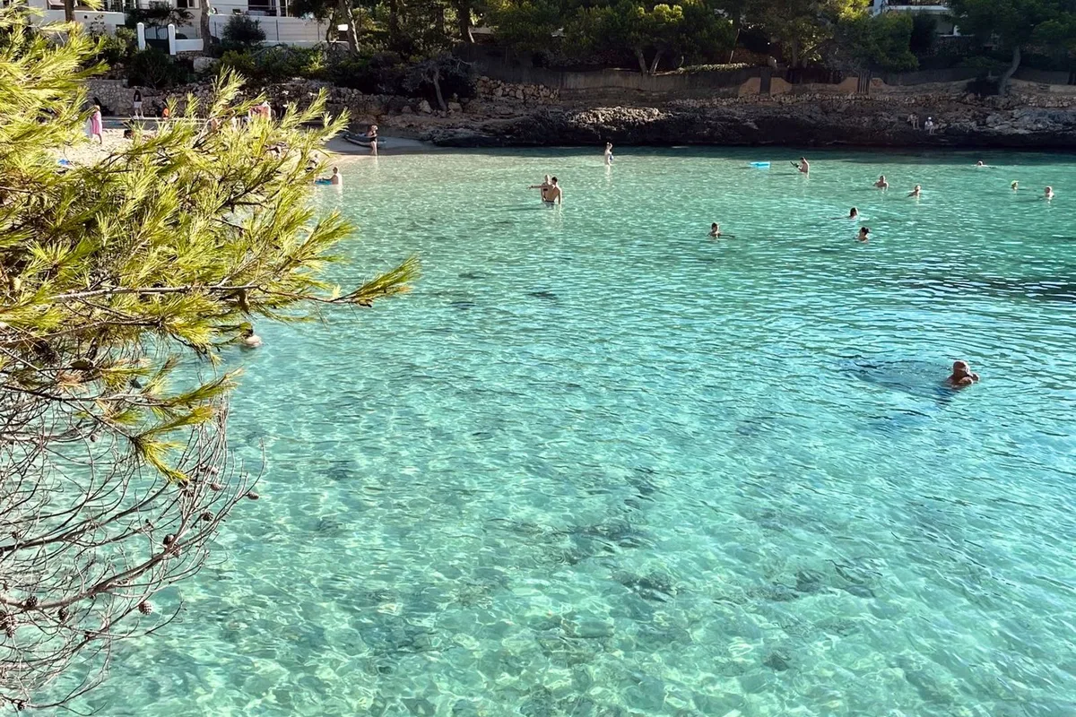 Swimmers in the clear turquoise water of an Ibiza cala