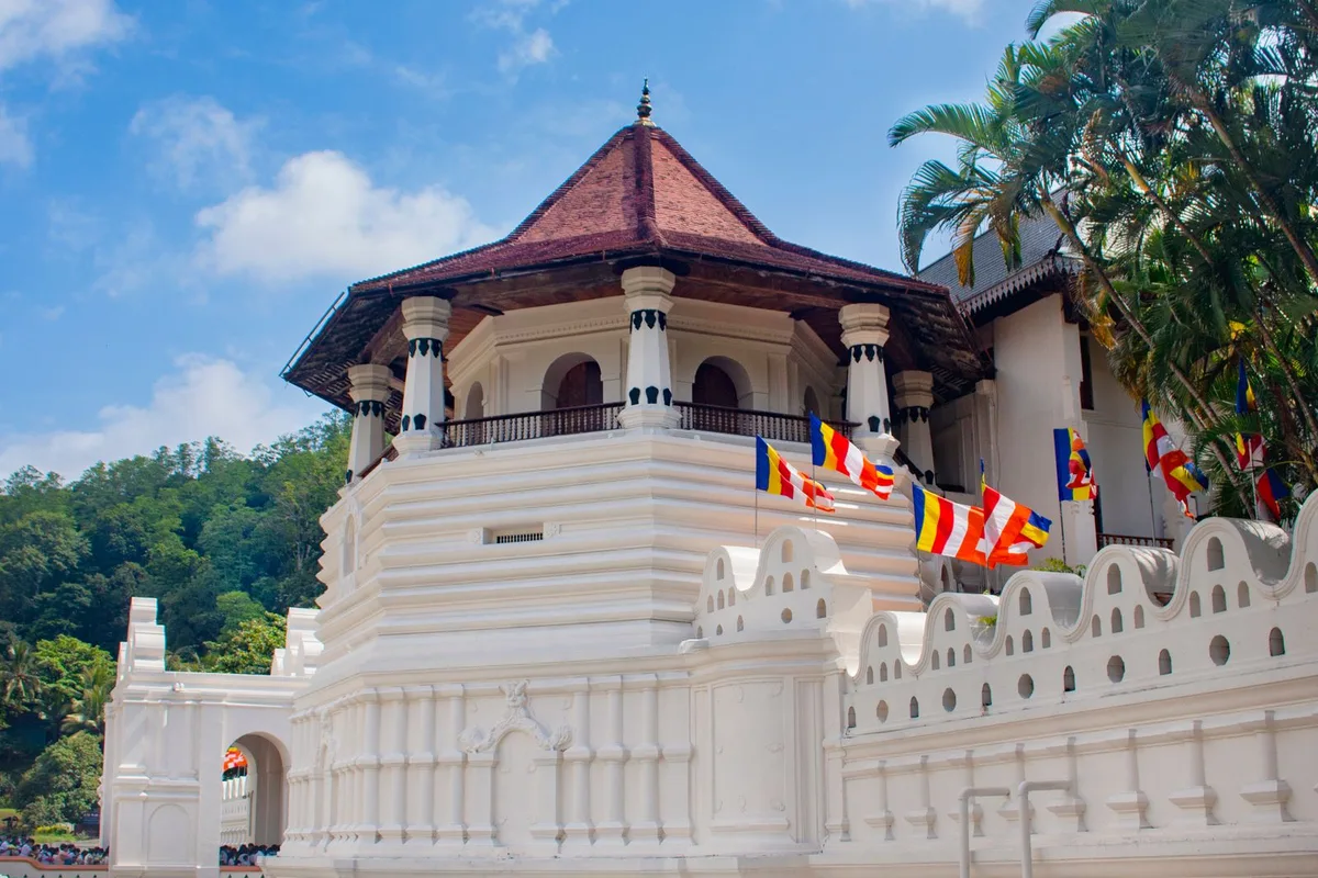 The Temple of the Sacred Tooth Relic in Kandy, its white pavilion and red roof against a blue sky