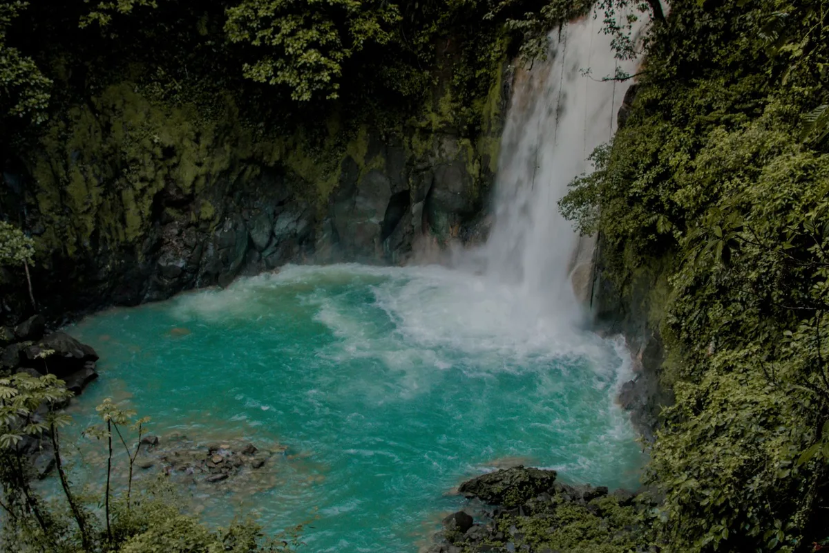 A waterfall pouring into the blue water of Río Celeste