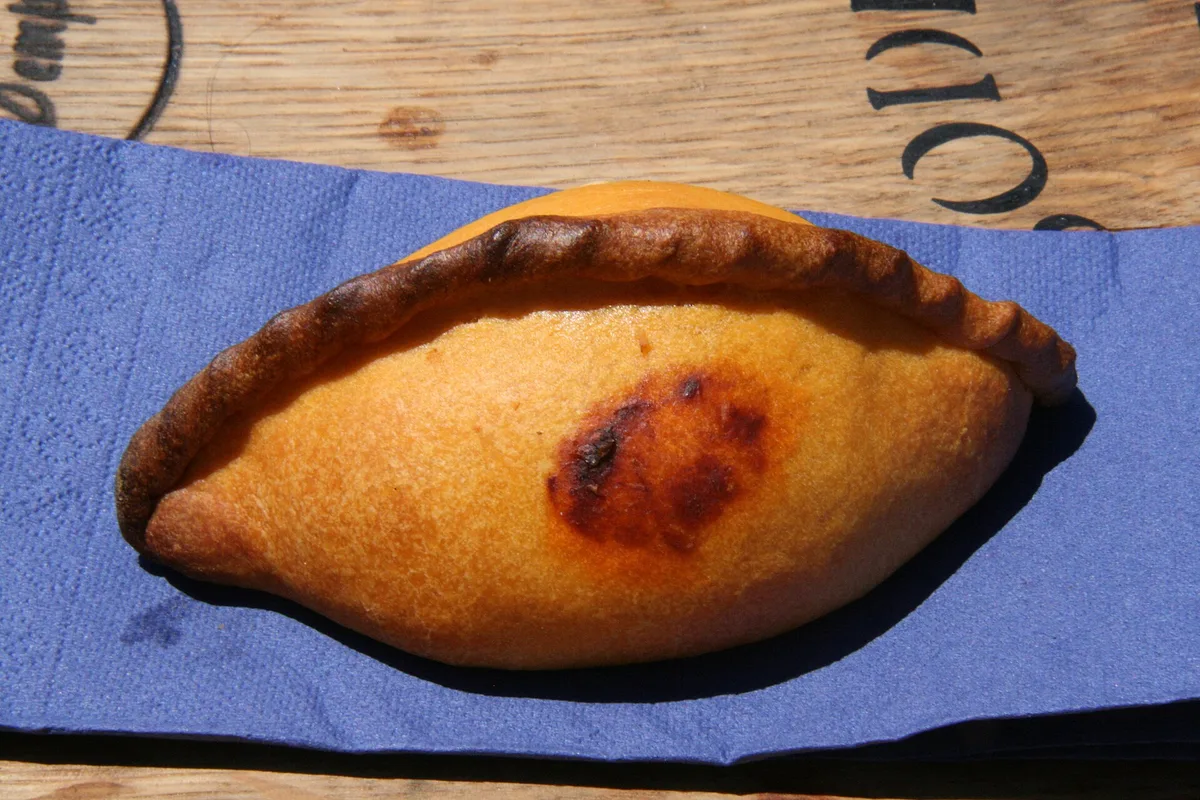 A golden salteña, Bolivia's baked morning empanada, on a café counter