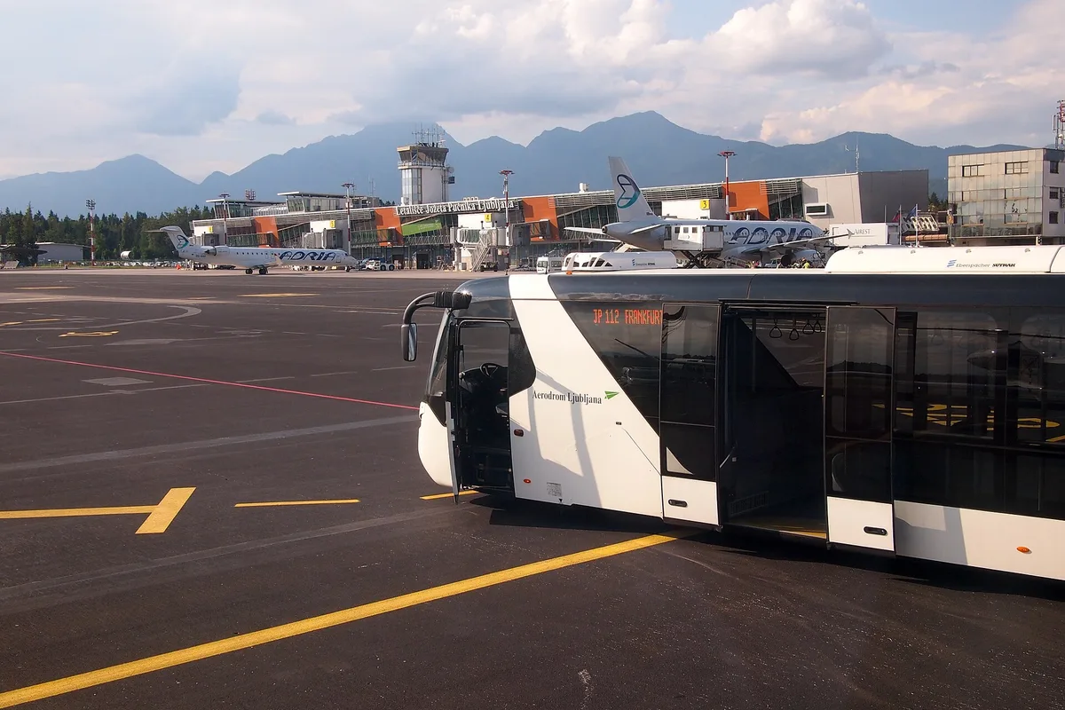 The tarmac at Ljubljana Jože Pučnik Airport, with the terminal, tower and an airport bus