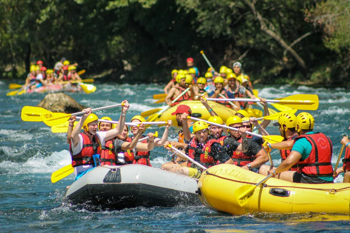 Rafters paddling white water in a mountain valley