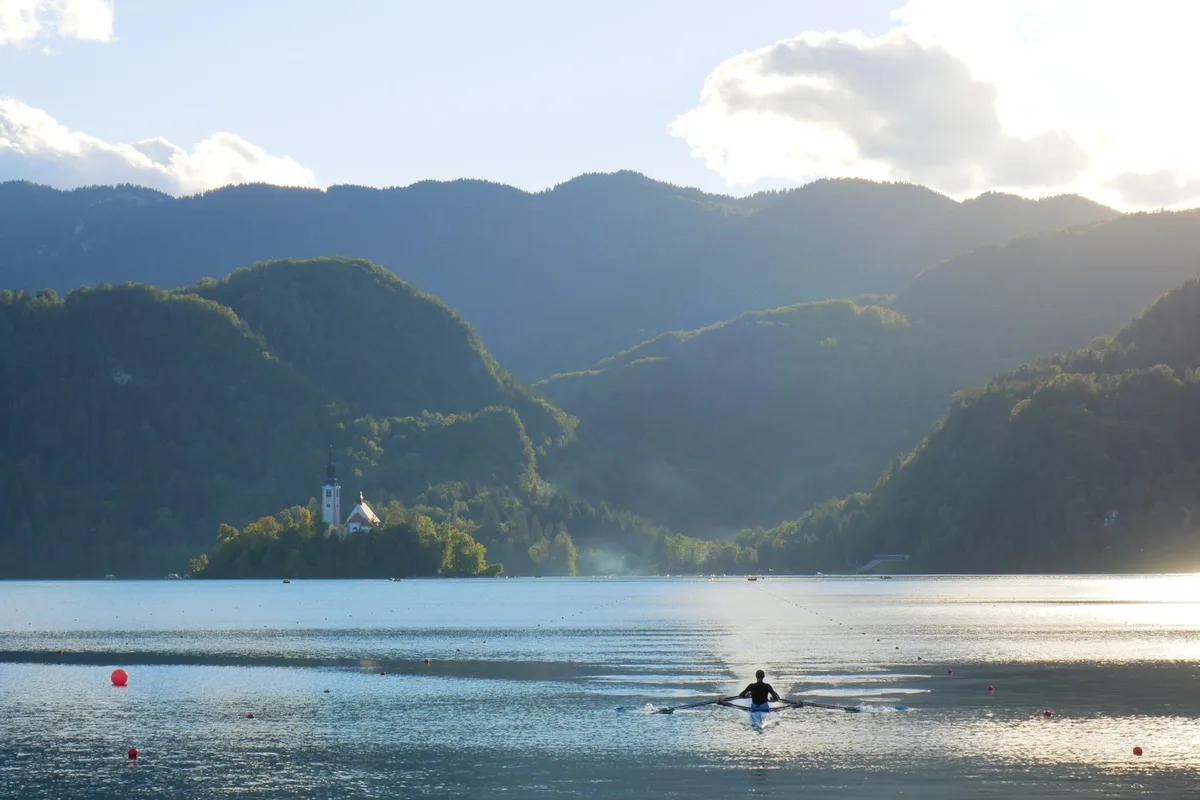 Morning light over Lake Bled, a rower crossing towards the island