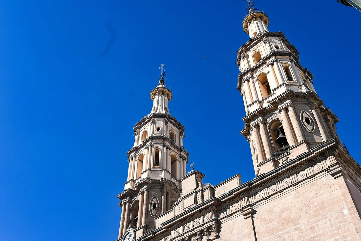 The twin towers of León Cathedral Basilica against a deep blue sky