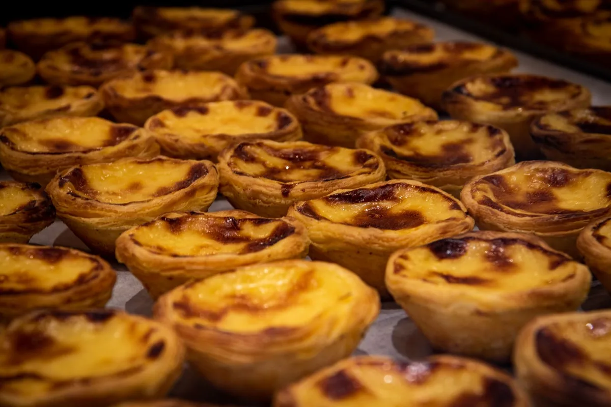 A tray of Portuguese egg tarts, blistered and golden, fresh from the oven