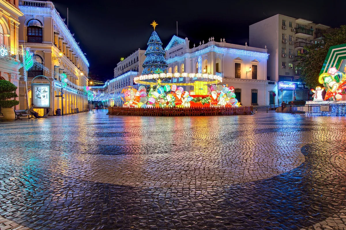Senado Square at night, its wave-patterned mosaic pavement shining after rain