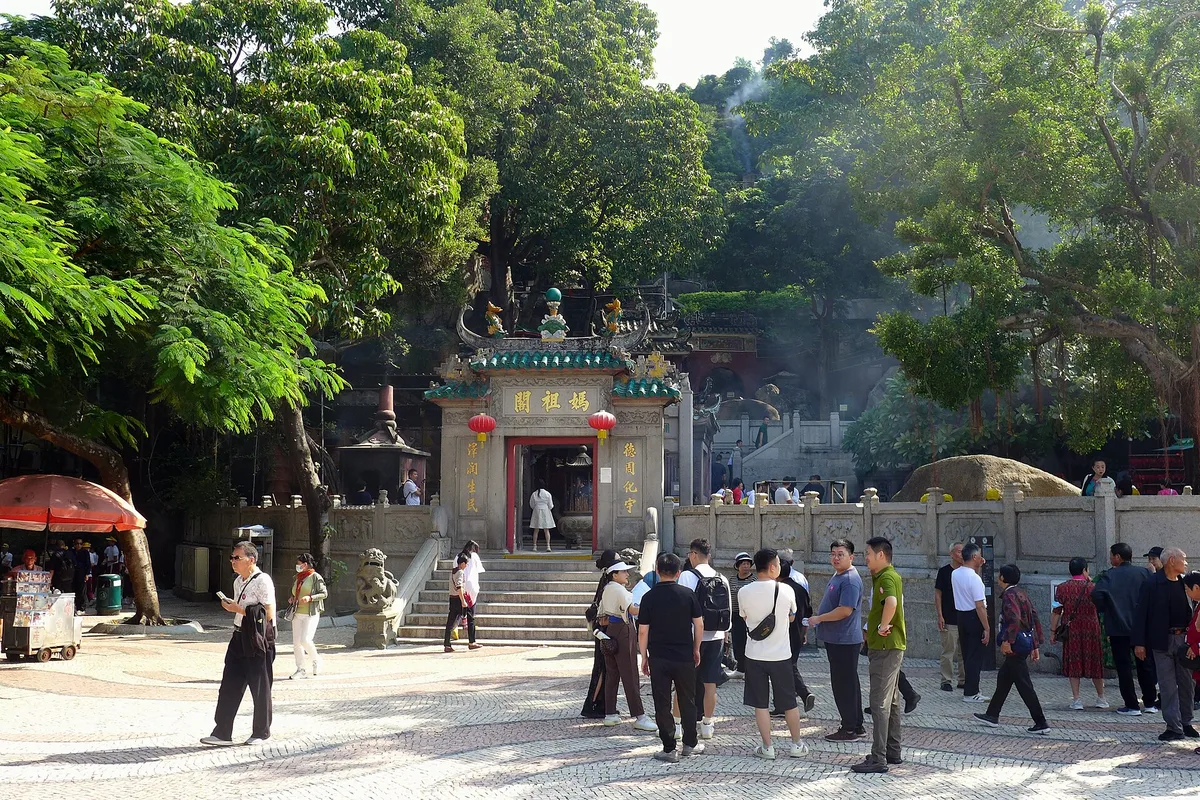 The entrance gate of A-Ma Temple, visitors on the mosaic plaza below the hill