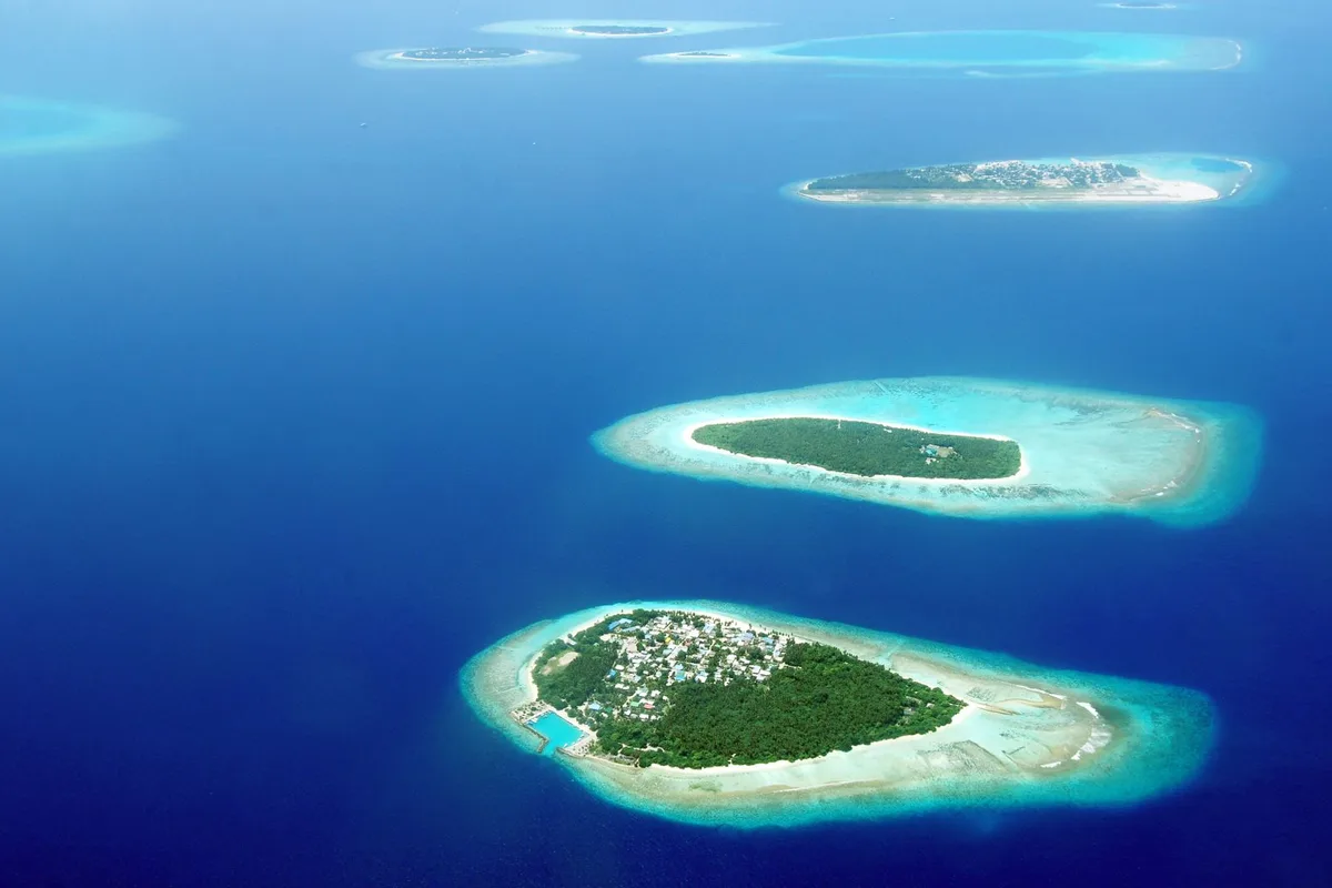 An aerial sweep over Maldivian islands and turquoise lagoon at first light