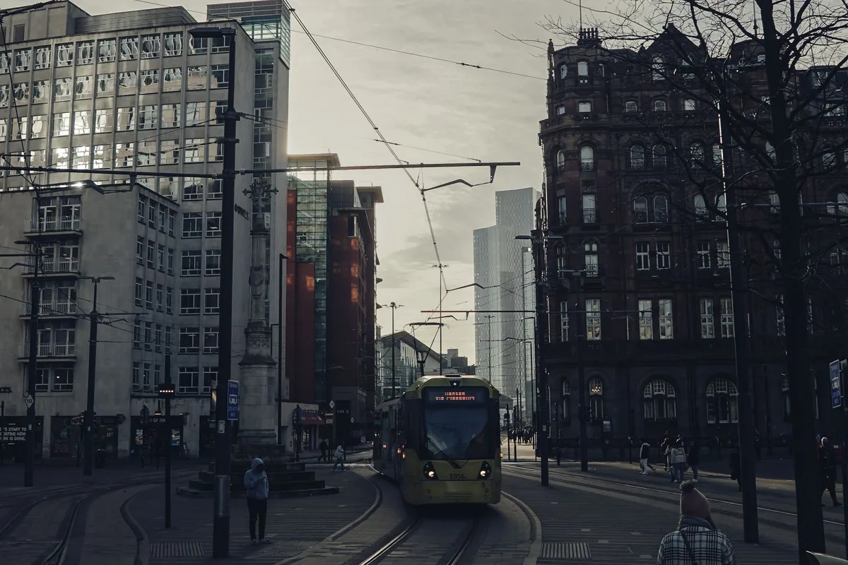 A yellow Metrolink tram approaching through the city centre