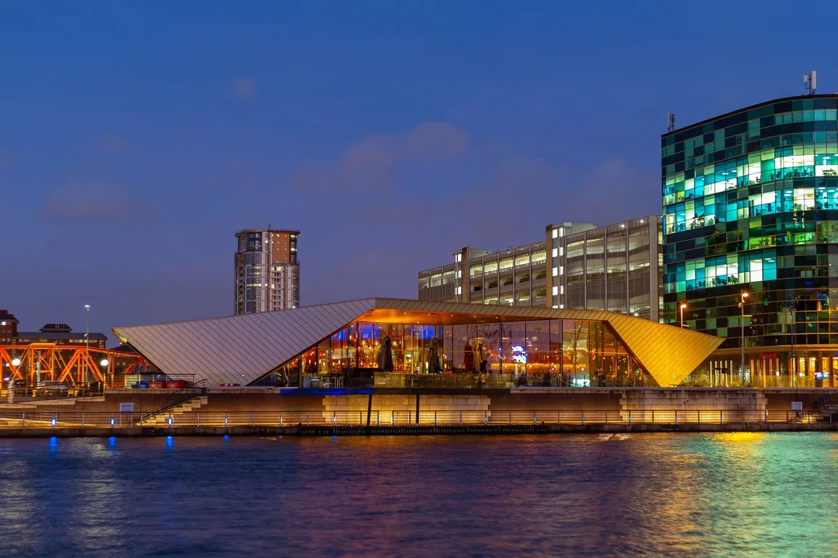 The Lowry and Salford Quays lit up at dusk across the ship canal