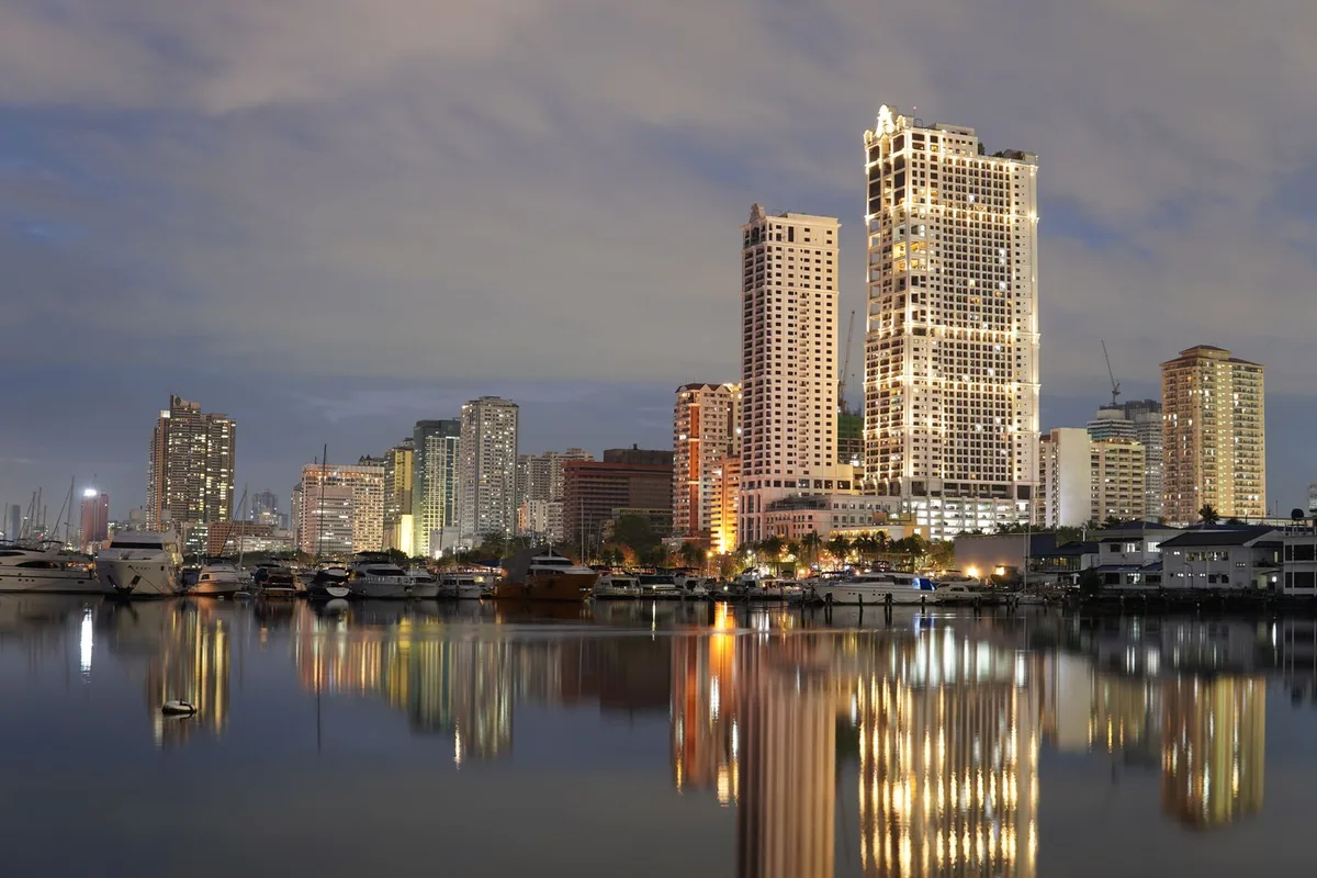 Bayfront towers at dusk reflected in the still water of the Manila Bay harbour