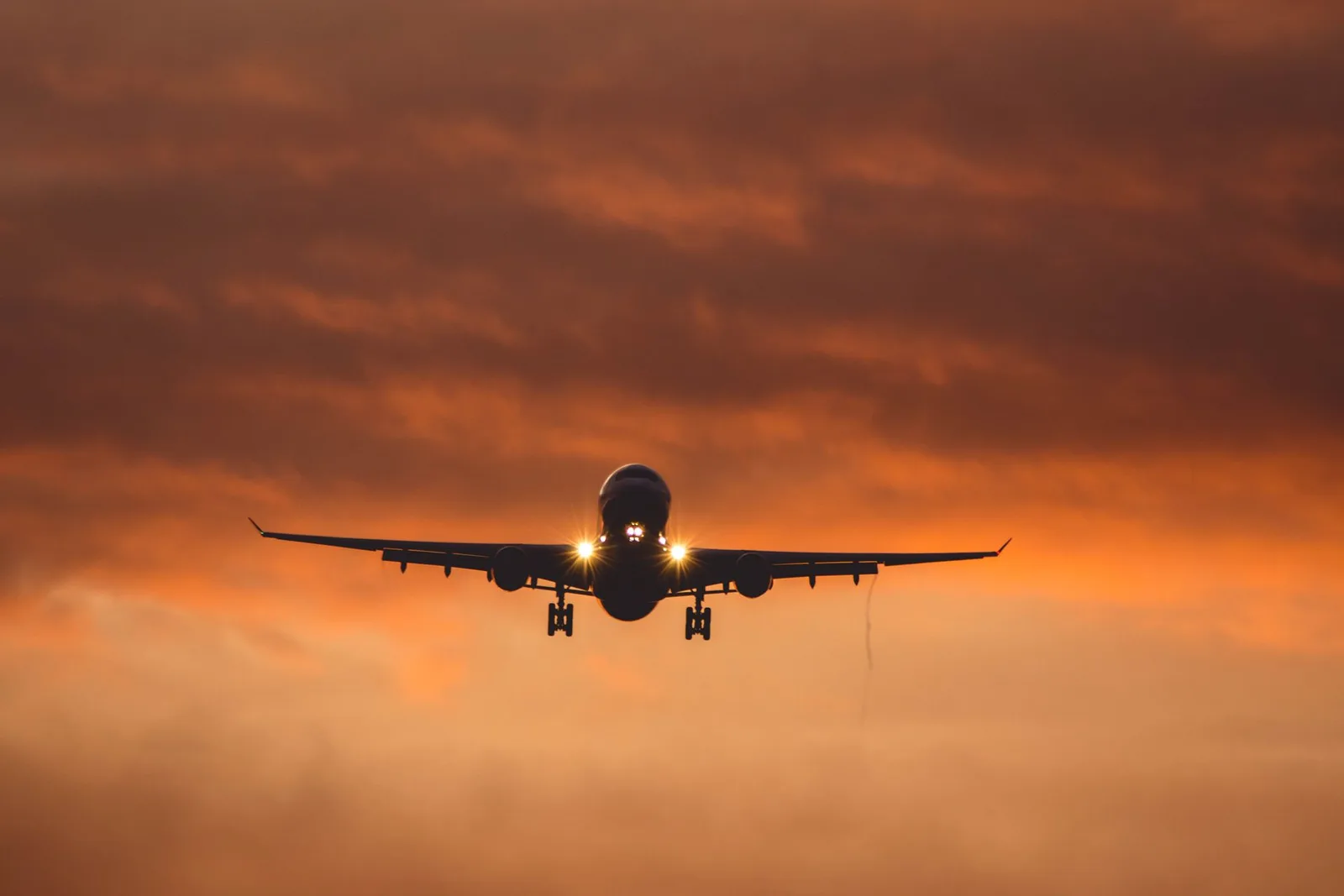 A jet on final approach against an orange sky