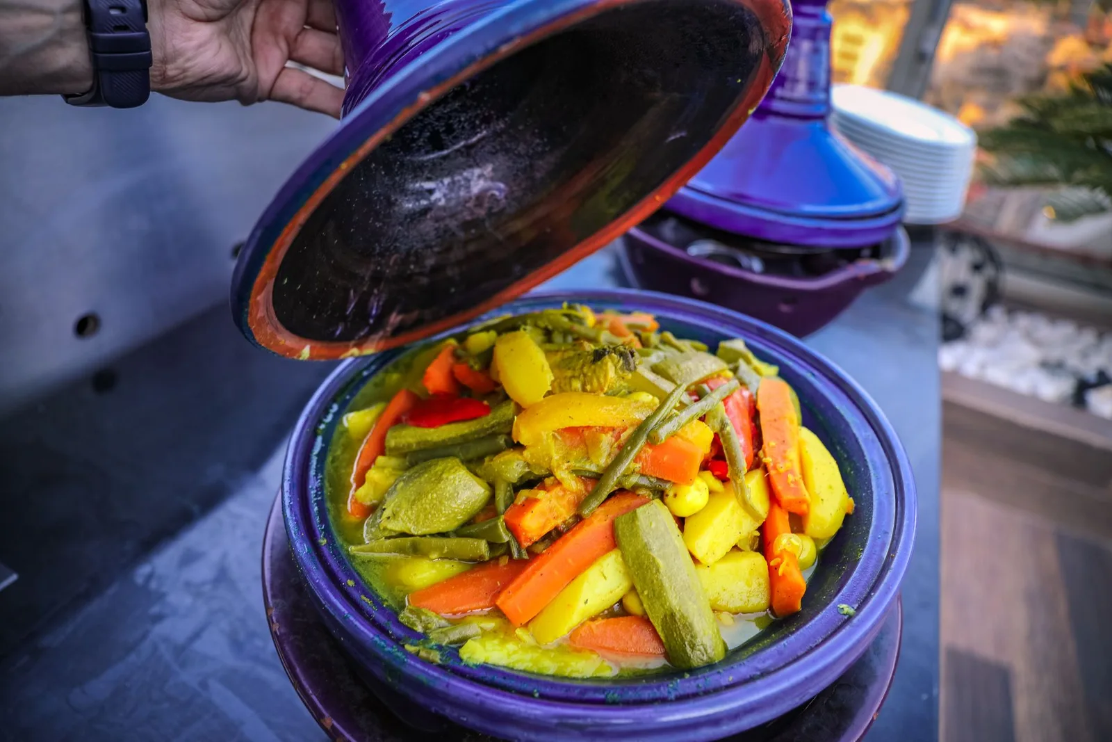 A vegetable tagine steaming as the lid is lifted