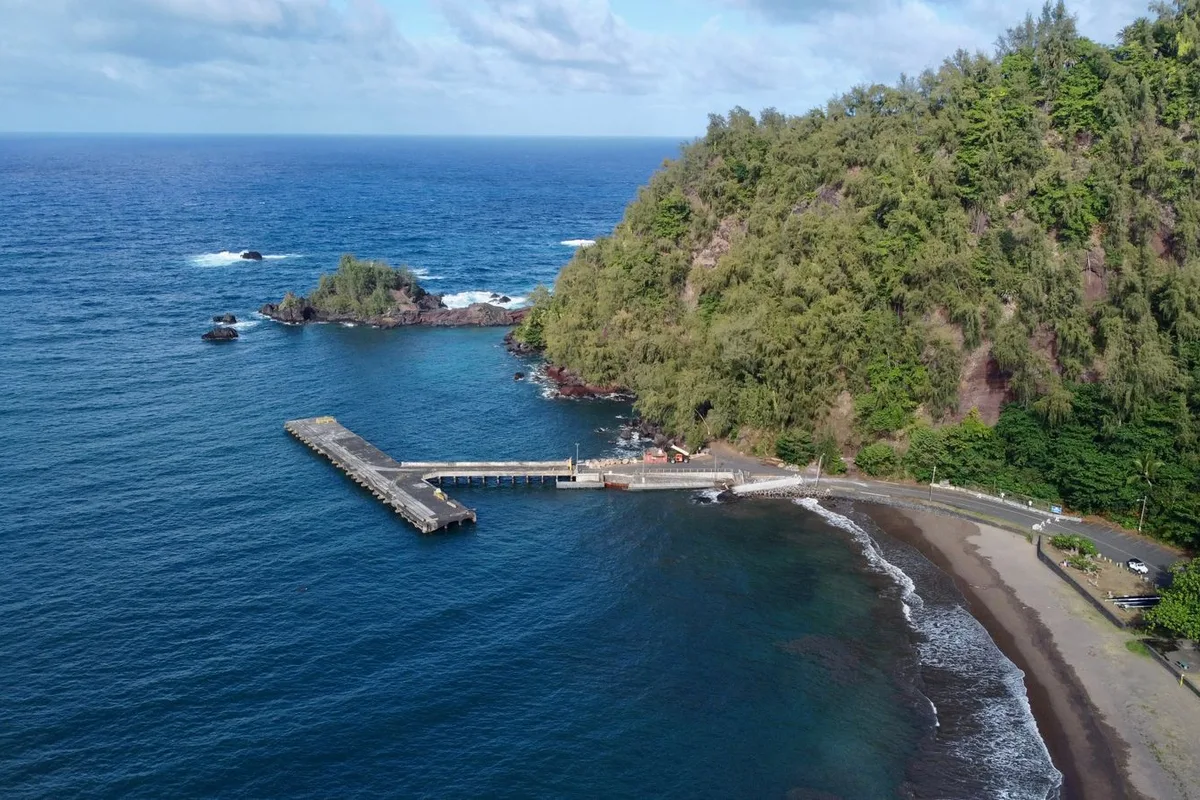 Hana Bay from the air, its pier reaching into the Pacific beside the dark-sand shore