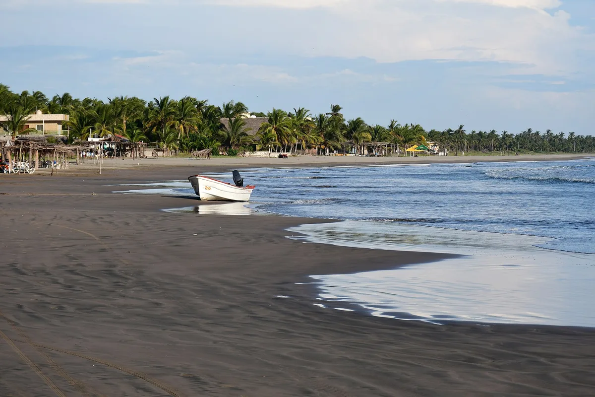 The palm-backed beach at Isla de la Piedra, a fishing boat pulled up on the sand