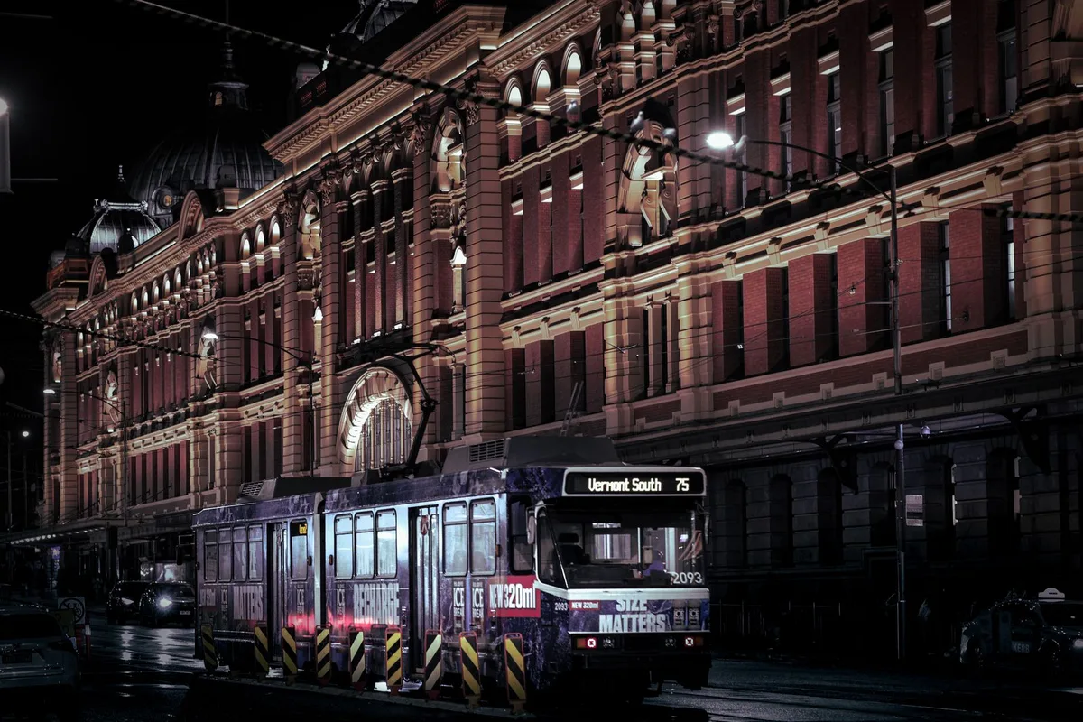 A city tram passing Flinders Street Station at night