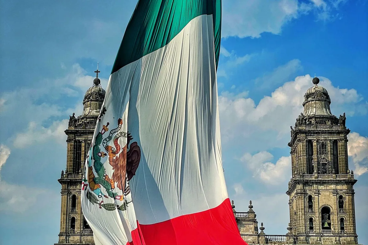 The Mexican flag raised over a colonial cathedral square
