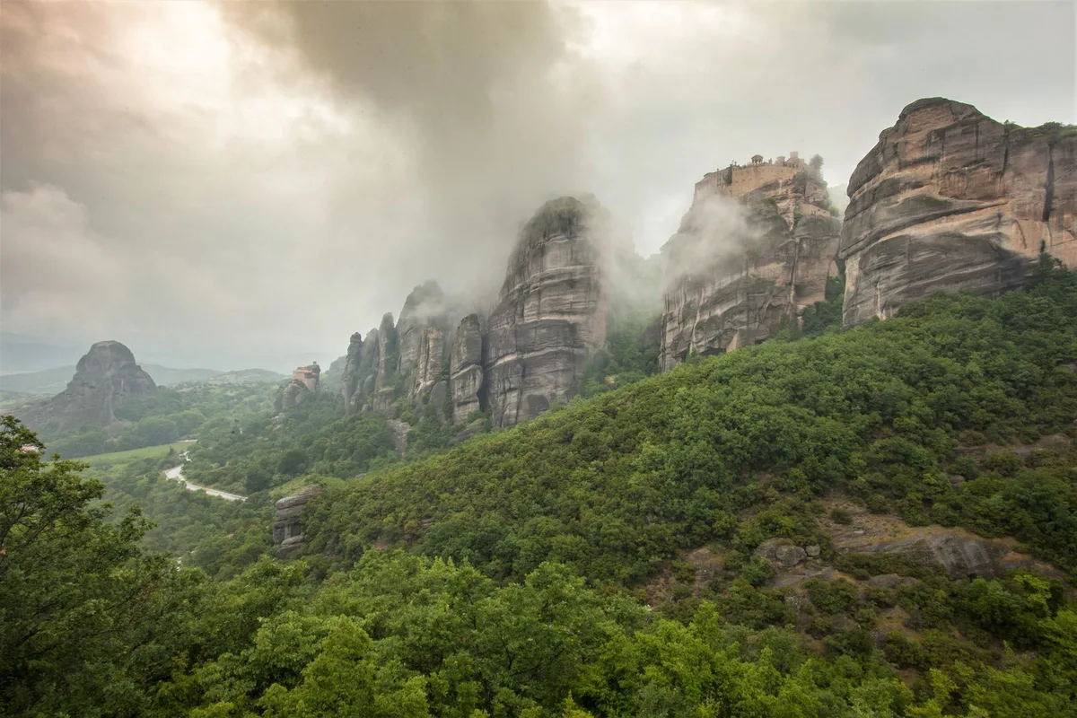Mist drifting between the green pillars of Meteora