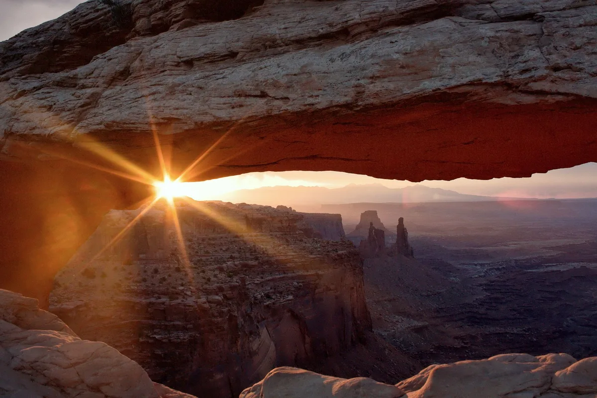 Sunrise through Mesa Arch in Canyonlands National Park, the Washer Woman tower beyond