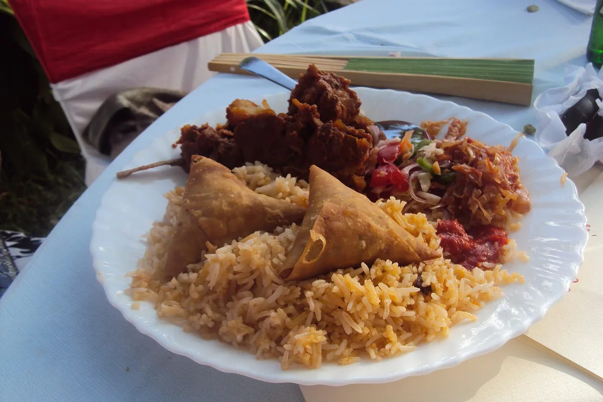 A Mombasa Island plate of pilau with samosa, fried mutton and kachumbari salad