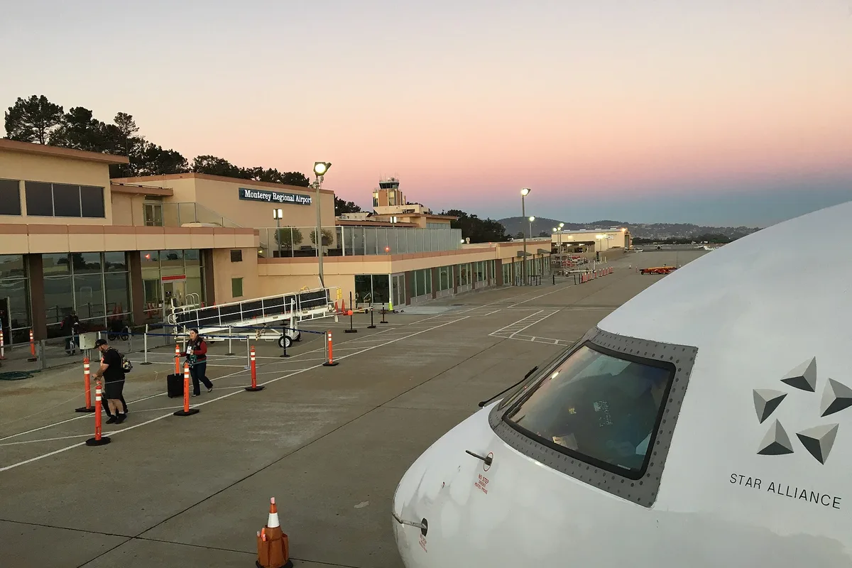 A United Express jet at the gate at Monterey Regional Airport at sunrise, passengers boarding on the tarmac