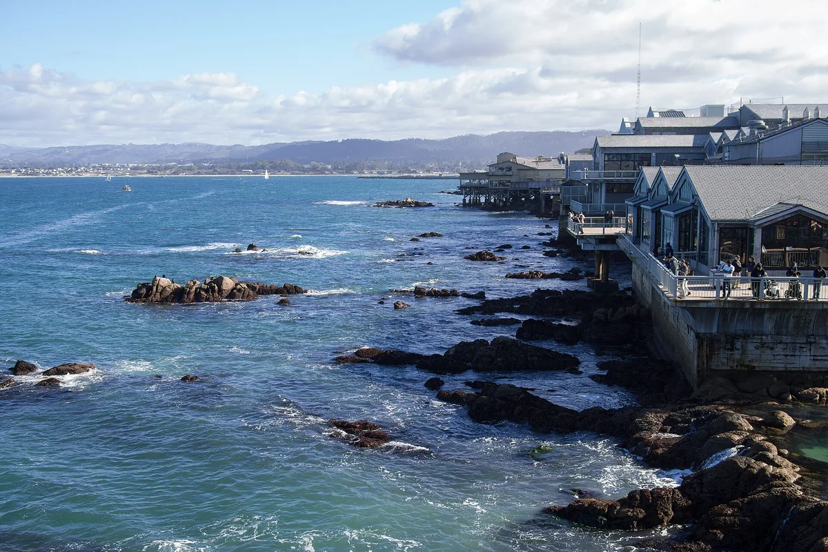 The Cannery Row shoreline in Monterey, waterfront buildings above the rocky bay