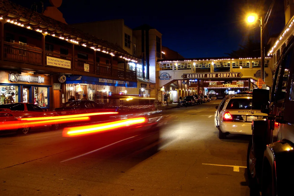 Cannery Row at night, restaurant lights and passing traffic on the historic sardine-canning street