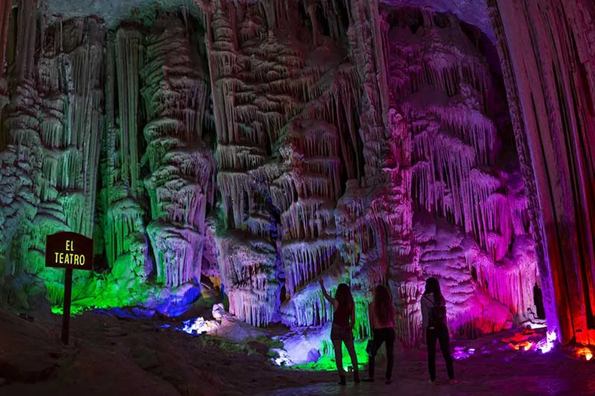 The colour-lit El Teatro chamber inside the Grutas de García