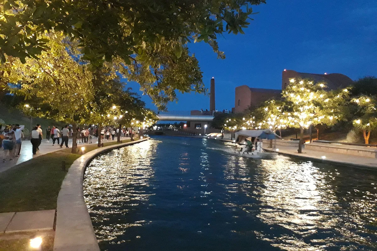 The Paseo Santa Lucía canal at dusk, a boat passing the lit walkways