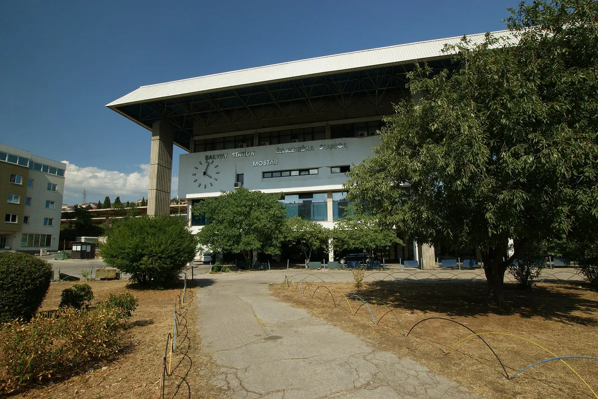 Mostar railway station, the brutalist terminal building with its clock and Mostar sign