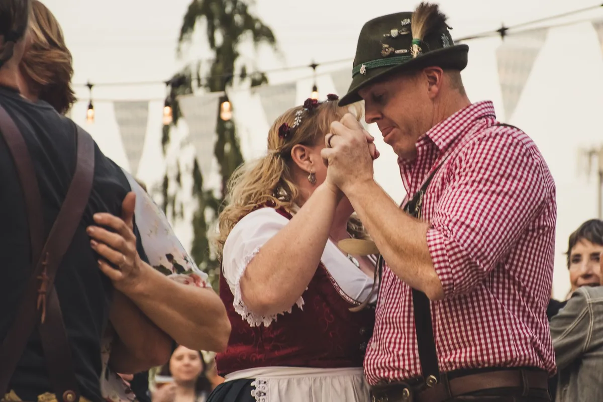 A couple in dirndl and lederhosen dancing at a Munich festival