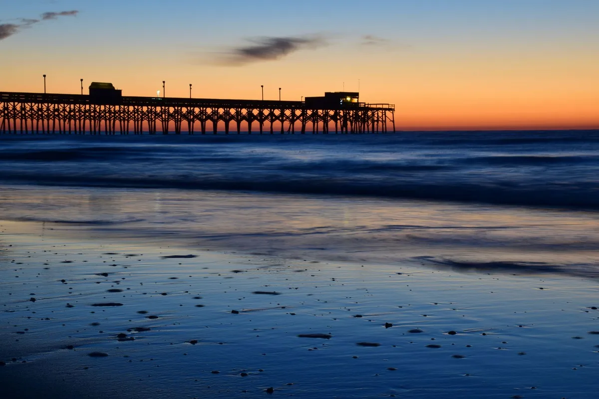 A Myrtle Beach fishing pier silhouetted against a sunset sky