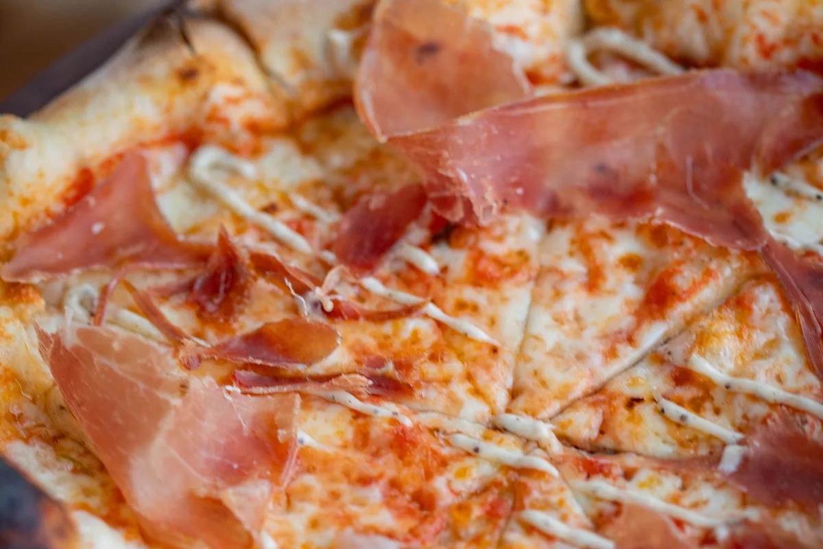 A wood-fired pizza with a blistered, leopard-spotted crust