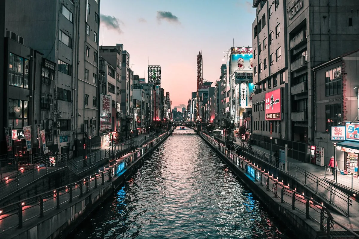 The Dotonbori canal at dusk, neon signs reflected in the water