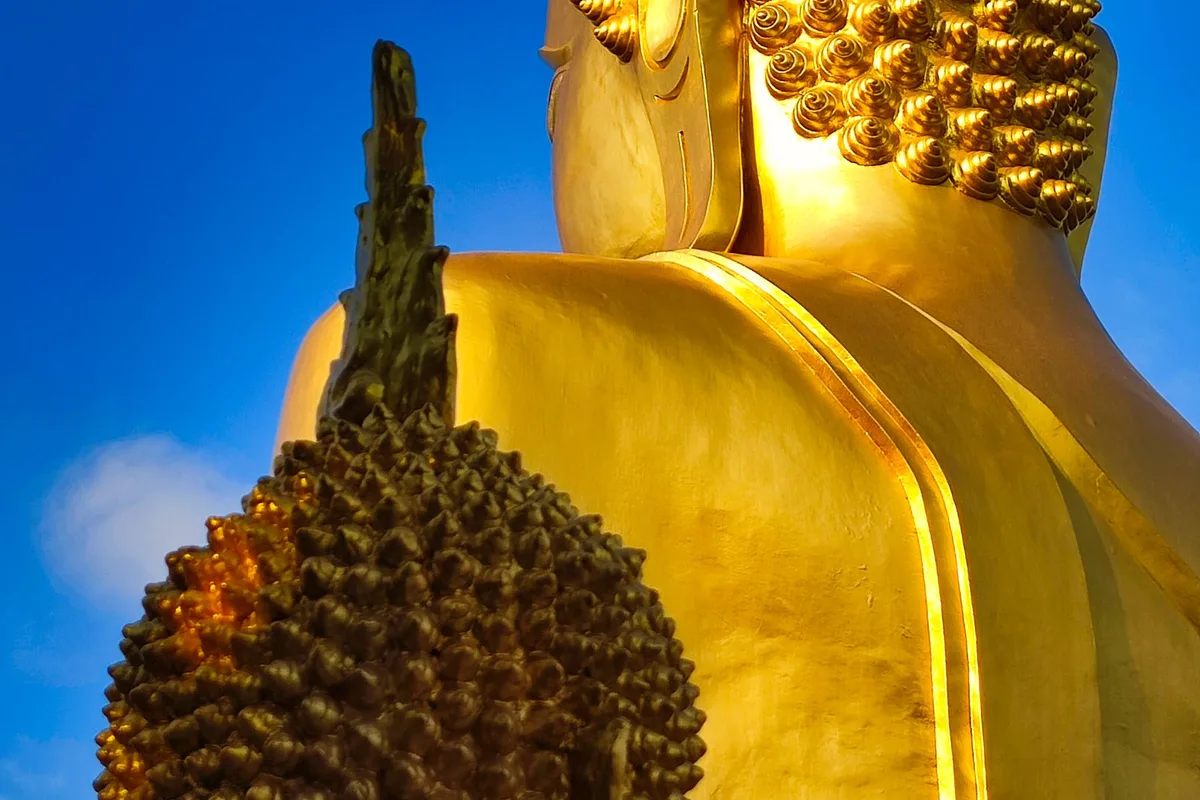 A golden Buddha image against the sky at a Thai temple