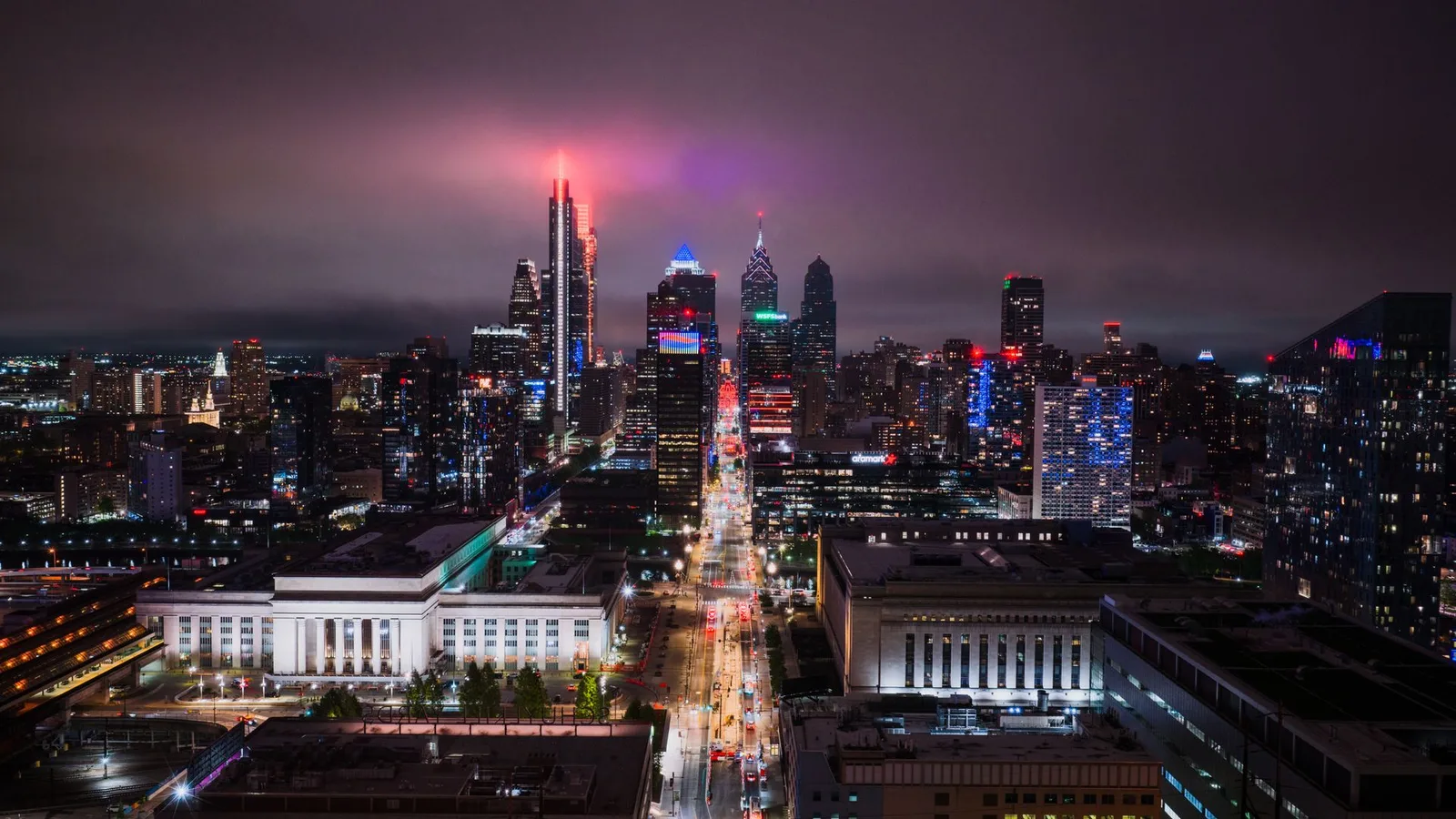 the Center City skyline at night from 30th Street Station, towers lit in colour