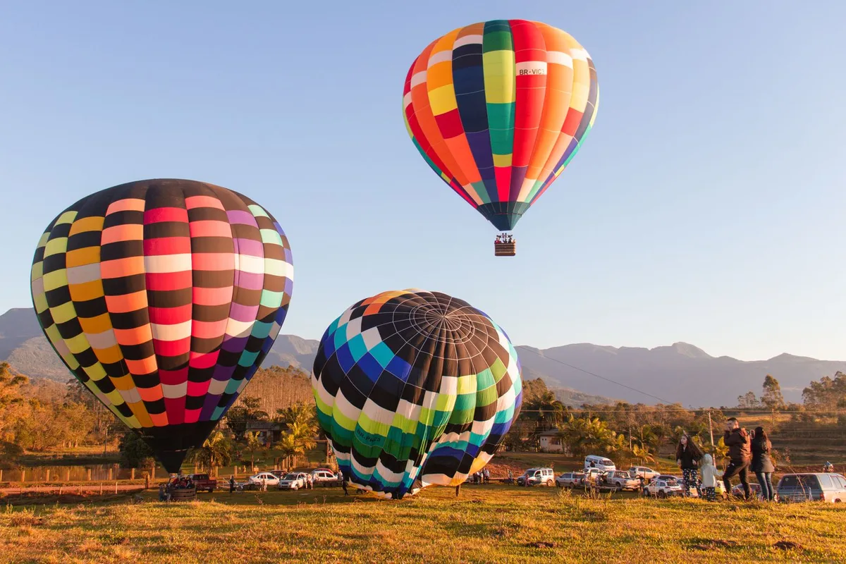 Hot air balloons drifting over desert hills at sunrise