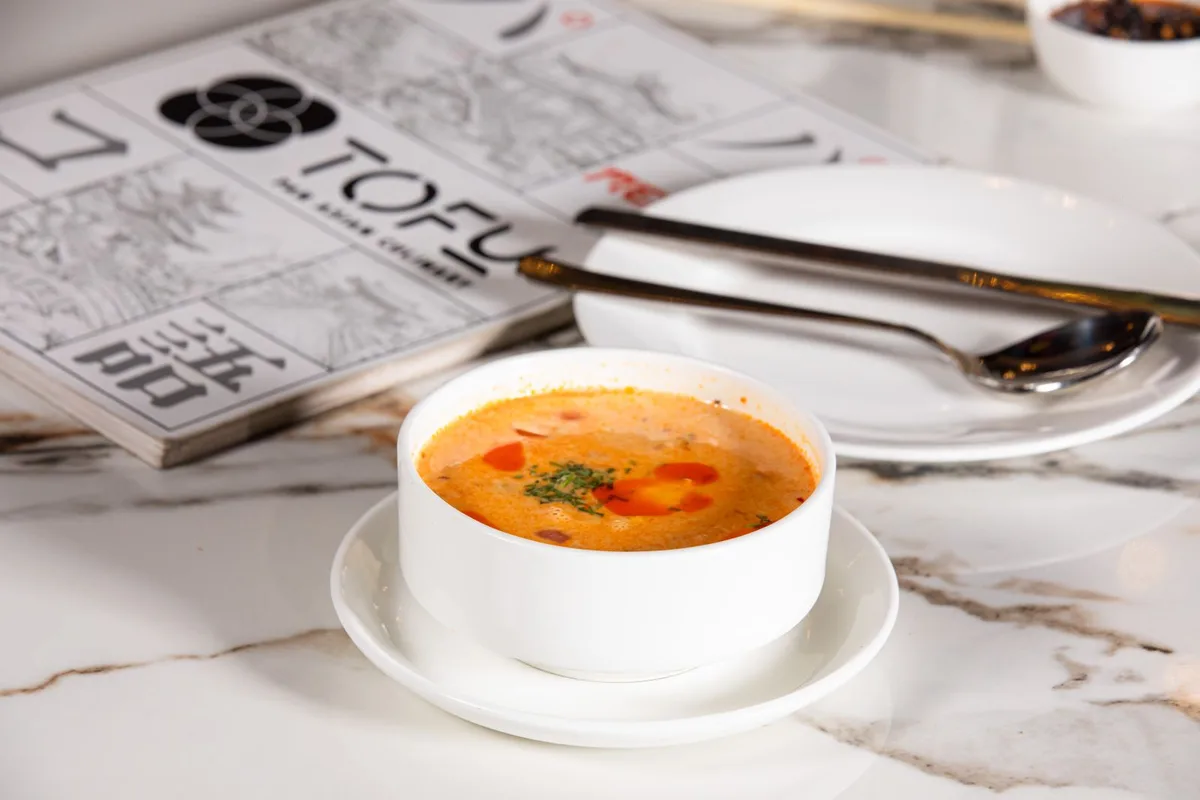 A bowl of tom yum soup with prawns, served with rice