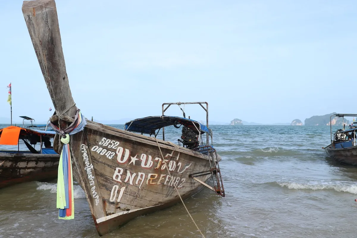 The carved bow of a longtail boat at the water's edge in Phuket