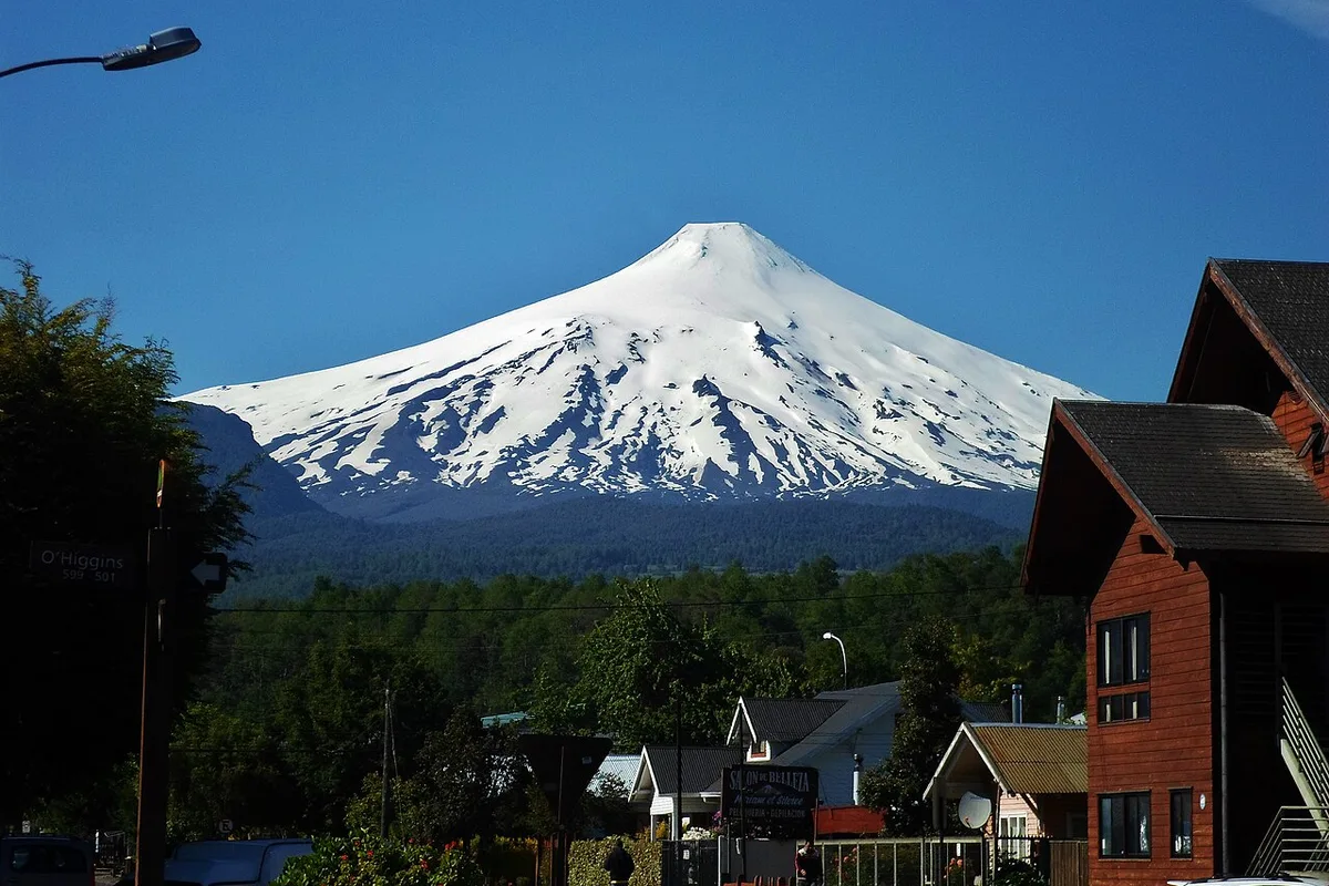 The snow-capped Villarrica volcano rising over the wooden buildings of Pucón