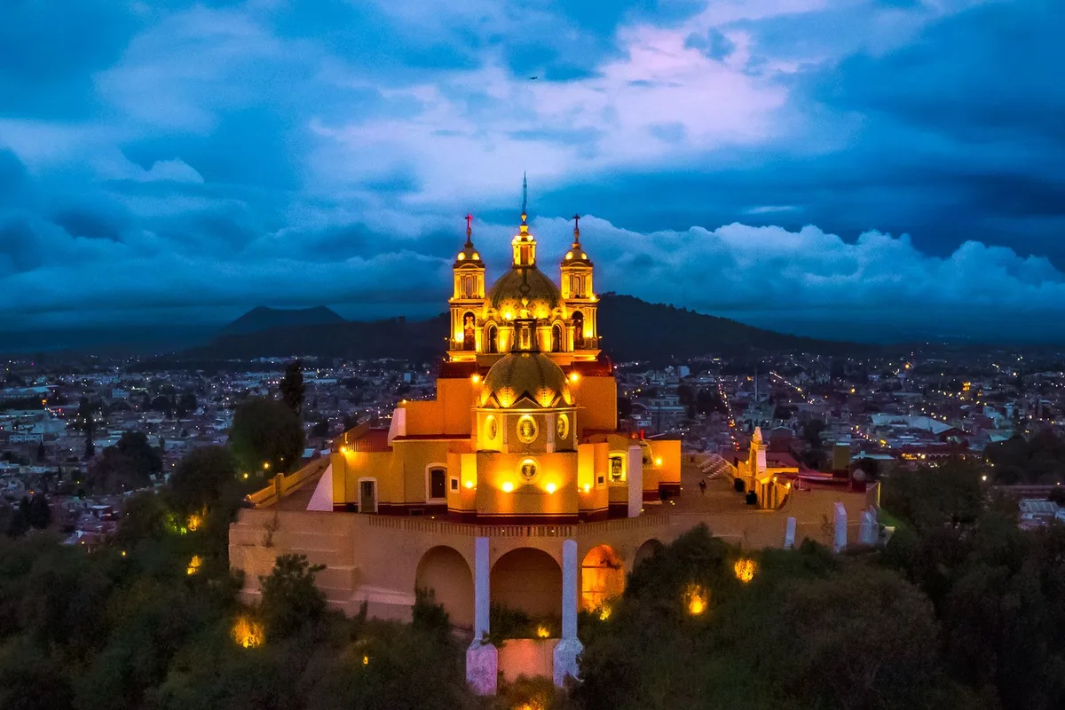 The church of Nuestra Señora de los Remedios lit up at dusk on top of the Great Pyramid of Cholula