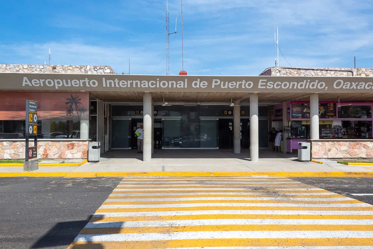 The terminal front of Puerto Escondido International Airport, the name spelled across the canopy above arrivals